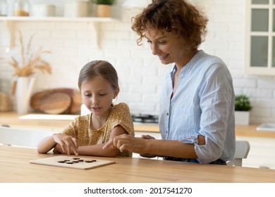 Smiling mother with little daughter having fun, playing logic wooden board game at kitchen table together, happy mom and curious girl engaged in educational activity, spending leisure time at home - Shutterstock ID 2017541270