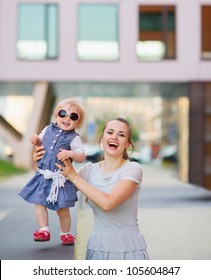 Smiling Mother Playing With Baby In City