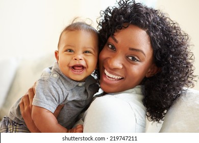 Smiling Mother Playing With Baby Son At Home