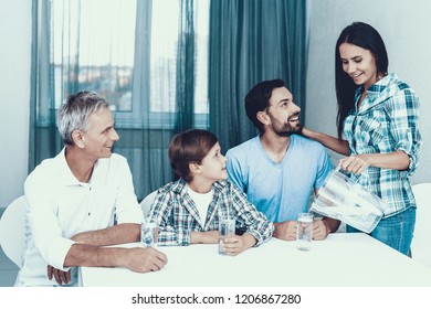 Smiling Mother Pouring Water In Glasses At Home. Father And Son. Smiling People. Parenthood Concept. Family At Home. Happy Family. Glass Of Water. Young Woman. Family In Dining Room.