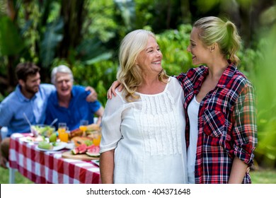 Smiling mother-in-law and daughter-in-law standing at yard