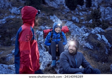 Smiling mountaineers wearing headlamps in the mountains at dusk