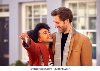 Smiling Multi Cultural Couple Outdoors On Moving Day Holding Keys To New Home In Fall Or Winter