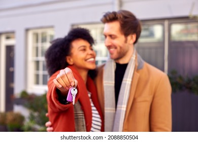 Smiling Multi Cultural Couple Outdoors On Moving Day Holding Keys To New Home In Fall Or Winter