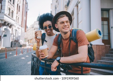 smiling multicultural couple of tourists standing with disposable cups of coffee 