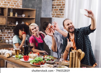 smiling multicultural friends taking selfie with smartphone in kitchen - Powered by Shutterstock