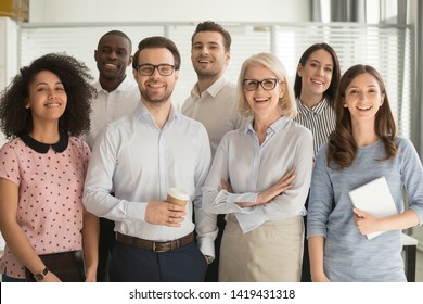 Smiling multiethnic employees standing looking at camera making team picture in office together, happy diverse work group or department laugh posing for photo at workplace, show unity and cooperation - Shutterstock ID 1419431318
