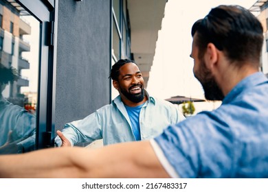 Smiling Multi-Ethnic male Couple talking in front of university building entrance door. Young Colleagues in casual talk outside work - Powered by Shutterstock