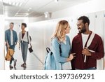 smiling multiethnic students looking at each other in corridor in college