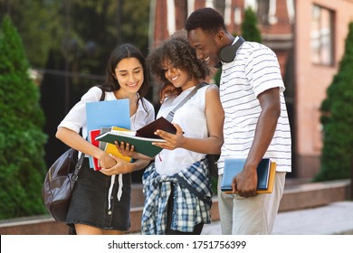 Smiling Multiethnic Students Standing Outdoors, Checking College Curriculum Together, Reading Information In Notebook