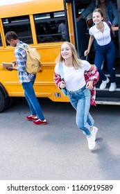 Smiling Multiethnic Teen Scholars Running Out School Bus 