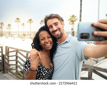 Smiling Multi-ethnic Young Couple Taking A Selfie On A Tropical Vacation. 