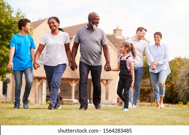 Smiling Multi-Generation Mixed Race Family Walking In Garden At Home