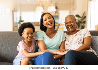 Smiling multigenerational family sitting on couch, enjoying quality time together. happiness, togetherness, bonding, indoor, grandmother, daughter, granddaughter - Powered by Shutterstock