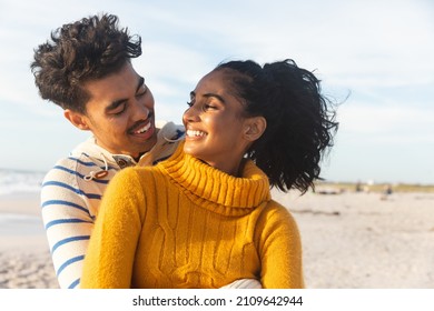 Smiling multiracial couple looking at each other while enjoying sunny day on beach. lifestyle, love and weekend. - Powered by Shutterstock