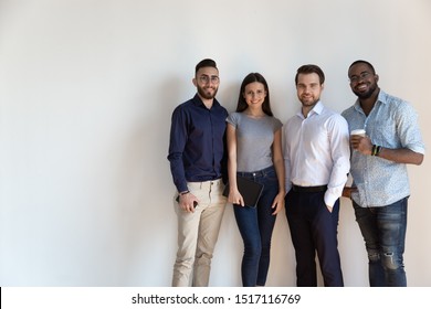 Smiling Multiracial Group Of International Company Workers Standing In Line Near White Wall. Successful Young Team Members Ready To Work, Portrait. Confident Diverse Business People Looking At Camera.