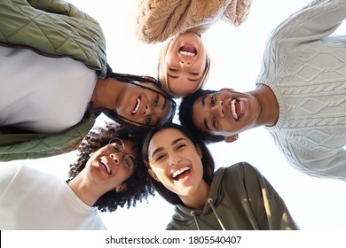 Smiling multiracial group of young friends forming circle of heads and looking at camera, friendship concept