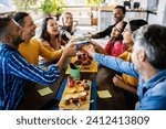 Smiling multiracial group of young people having breakfast together at coffee eatery shop