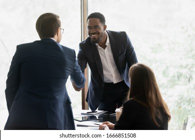 Smiling Multiracial Male Business Partners Handshake Greeting Getting Acquainted At Office Meeting, Happy Divers Multiethnic Man Colleagues Shake Hands Close Deal Or Make Agreement At Briefing