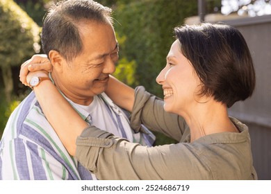 Smiling multiracial middle-aged couple embracing outdoors, enjoying quality time together in garden. Romance, happiness, togetherness, nature, affection, bonding - Powered by Shutterstock