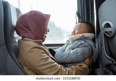 Smiling Muslim Mother And Toddler Sitting Inside The Bus Playing Together