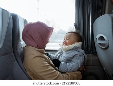Smiling Muslim Mother And Toddler Sitting Inside The Bus Playing Together