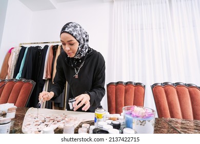 Smiling Muslim Woman Making Ornaments On Fabric With Paint