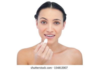 Smiling natural model using lip balm on white background