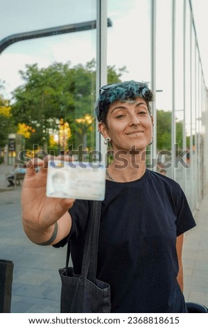 smiling non-binary person looking at camera with ID. non binary rights identity