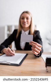 Smiling Notary Holding Blank Business Card On Blurred Background