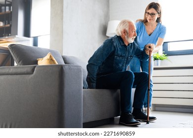 Smiling nurse assisting senior man to get up from bed. Caring nurse supporting patient while getting up from bed and move. Helping elderly disabled man standing up in his living room. - Powered by Shutterstock