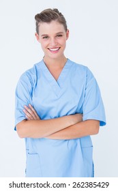 Smiling Nurse In Blue Scrubs Posing With Arms Crossed On White Background