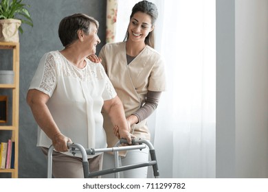Enfermera sonriente ayudando a las ancianas a caminar por la residencia
