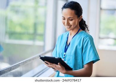 Smiling Nurse in Hospital Scrubs Using Digital Tablet in Modern Medical Facility - Powered by Shutterstock