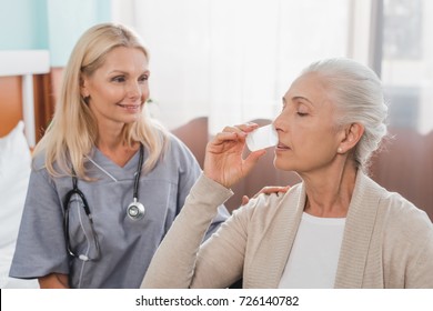 Smiling Nurse Looking At Senior Patient Taking Medicine