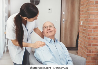 Smiling Nurse And Old Senior Man Patient At Home. Care For Older People Concept