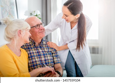 Smiling nurse talking with senior couple during home visit - Powered by Shutterstock