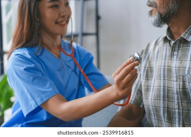 Smiling nurse using stethoscope checking heartbeat of senior patient during home visit, providing healthcare and medical assistance
