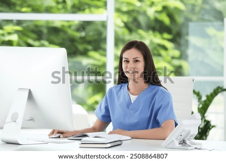 Smiling nurse working with computer at table in hospital office