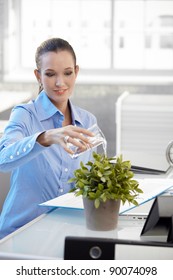 Smiling Office Worker Girl Watering Potted Plant, Sitting At Desk.?