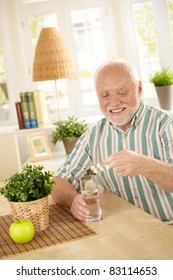 Smiling Old Man Taking Medication With Water, Holding Bubble Package, Sitting At Home.?