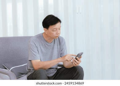 Smiling old man talking over smartphone while relaxing at home. Senior man after retirement using smart phone to connect with friends and family. - Powered by Shutterstock