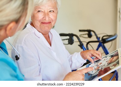 Smiling Old Woman With Dementia And Geriatric Nurse Look At Calendar With Baby Photo