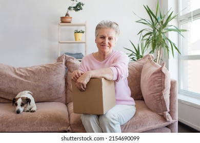 Smiling Older Adult Mature Woman Customer Unpacking Parcel Concept Sitting At Home On Couch. Happy Senior Middle Aged Lady Opening Online Store Order Receiving Gift In Postal Delivery Shipping Box.
