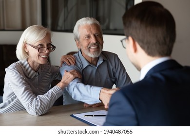 Smiling older Caucasian man and woman clients shake hand greeting get acquainted at meeting with specialist. Happy mature couple customers handshake close deal with real estate agent or broker. - Shutterstock ID 1940487055
