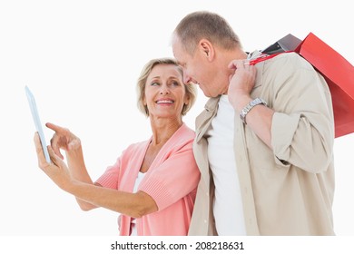 Smiling Older Couple Holding Shopping Bags Looking At Tablet Pc On White Background