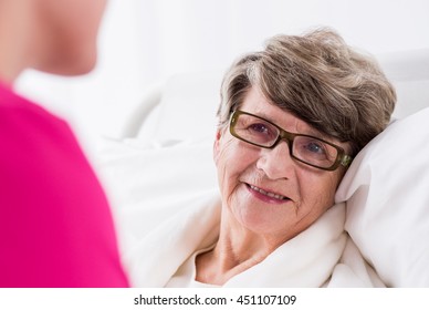 Smiling Older Female Patient Lying In Hospital Bed