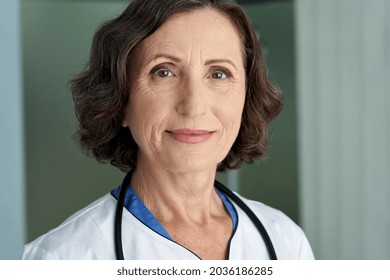 Smiling Older Senior Female Doctor Wearing Medical Coat Looking At Camera. Headshot Portrait Of Mature Old Woman Medic Professional, Hospital Physician, Confident Practitioner Or Surgeon At Work.