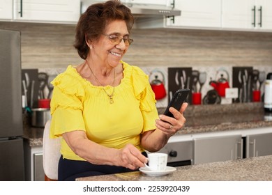 Smiling older woman consults her smartphone while holding a cup of coffee in the other hand. - Powered by Shutterstock