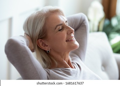 Smiling Older Woman Relaxing With Hands Behind Head On Cozy Sofa At Home, Happy Sincere Mature Female With Grey Hair Enjoying Weekend, Stretching On Couch, Resting And Daydreaming, Leaning Back